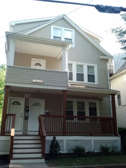 A two-story house with a white door and brown railings.