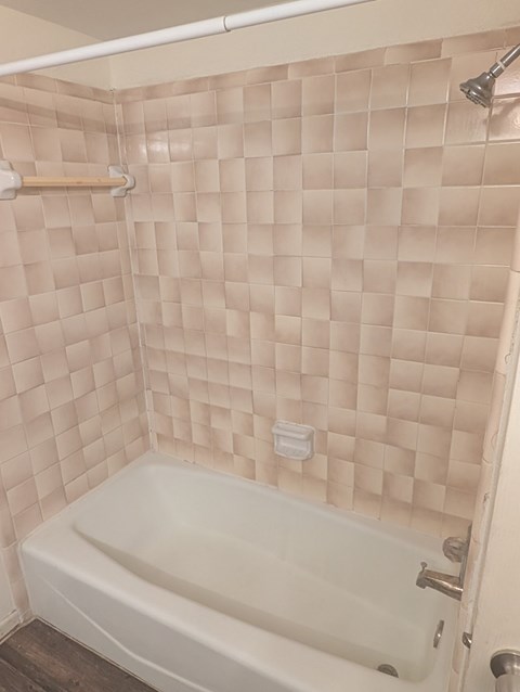 A white bathtub in a bathroom with pink tiles.