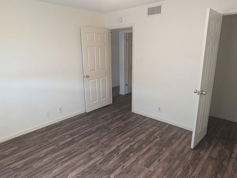 A room with a white door and a brown floor.