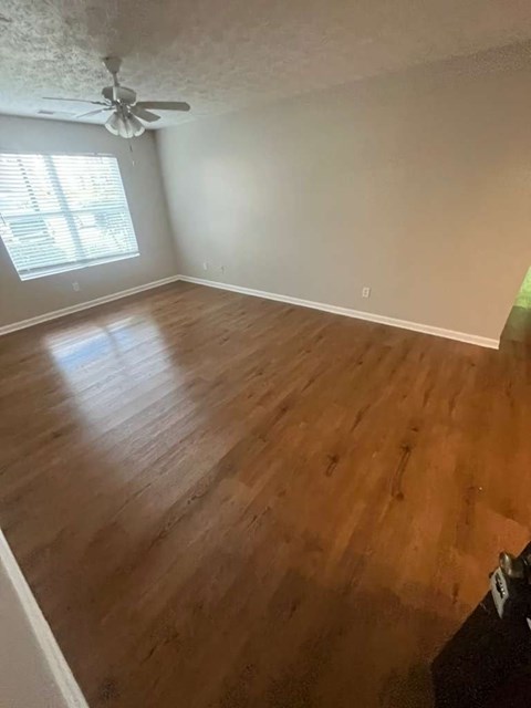 A room with a ceiling fan and wooden flooring.