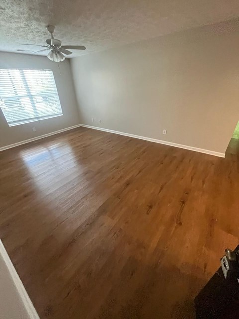 A room with a ceiling fan and wooden flooring.