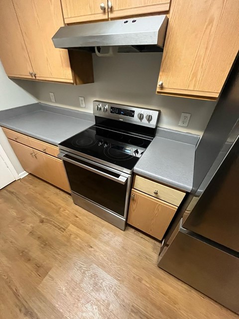 A modern kitchen with a stainless steel oven and wooden cabinets.