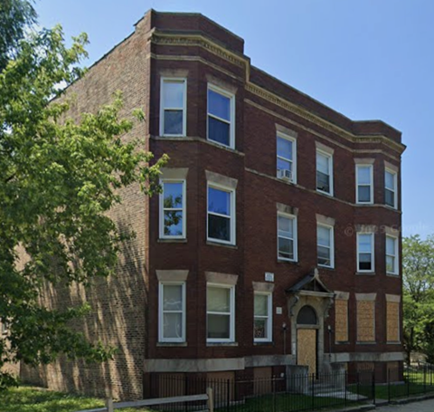 A red brick building with a black iron fence in front.
