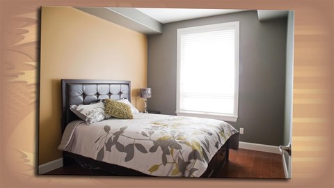 A bedroom with a bed, pillows, and a lamp.