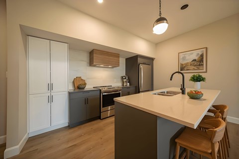 A kitchen with a white countertop and wooden chairs.