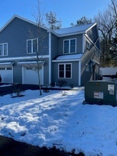 A house with a grey roof and a green trash bin in front of it.