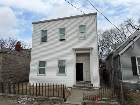 A white two-story house with a black door and windows.