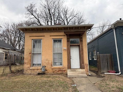 A small brown house with a white door and a small porch.