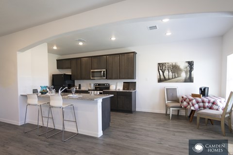 A kitchen with a bar area and a painting of trees on the wall.