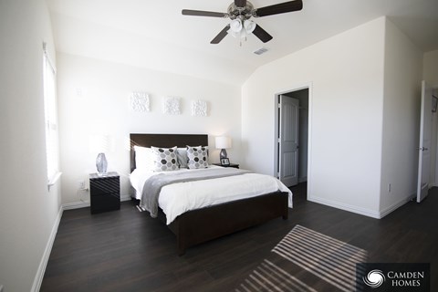 A bedroom with a bed, nightstand, and a ceiling fan.