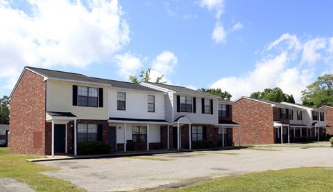 A row of houses with a gravel driveway in front.