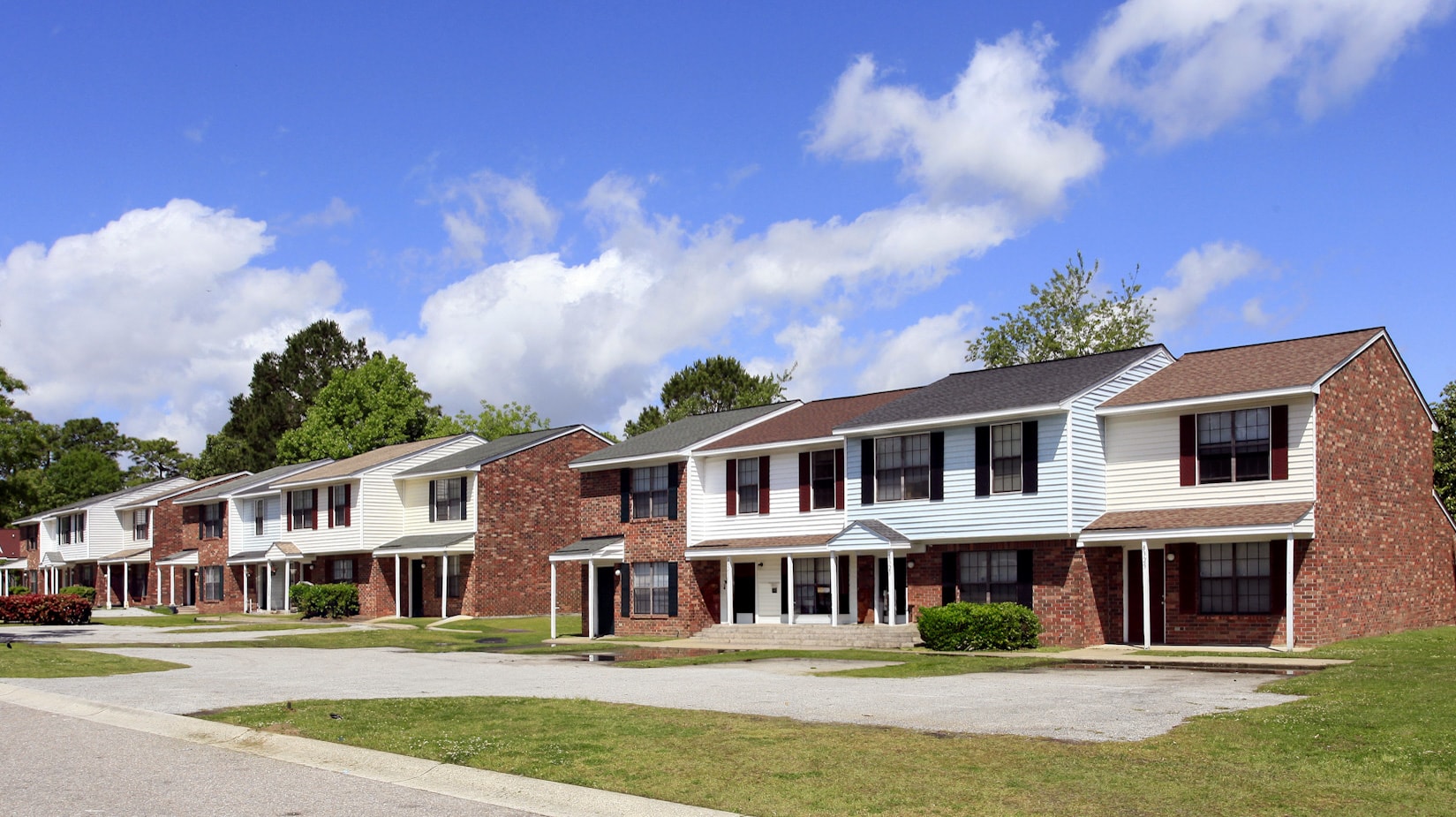 A row of houses with a blue sky and clouds in the background.