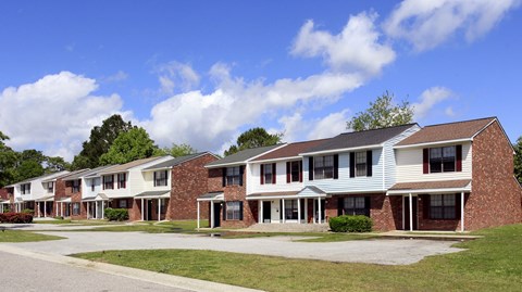 A row of houses with a blue sky and clouds in the background.