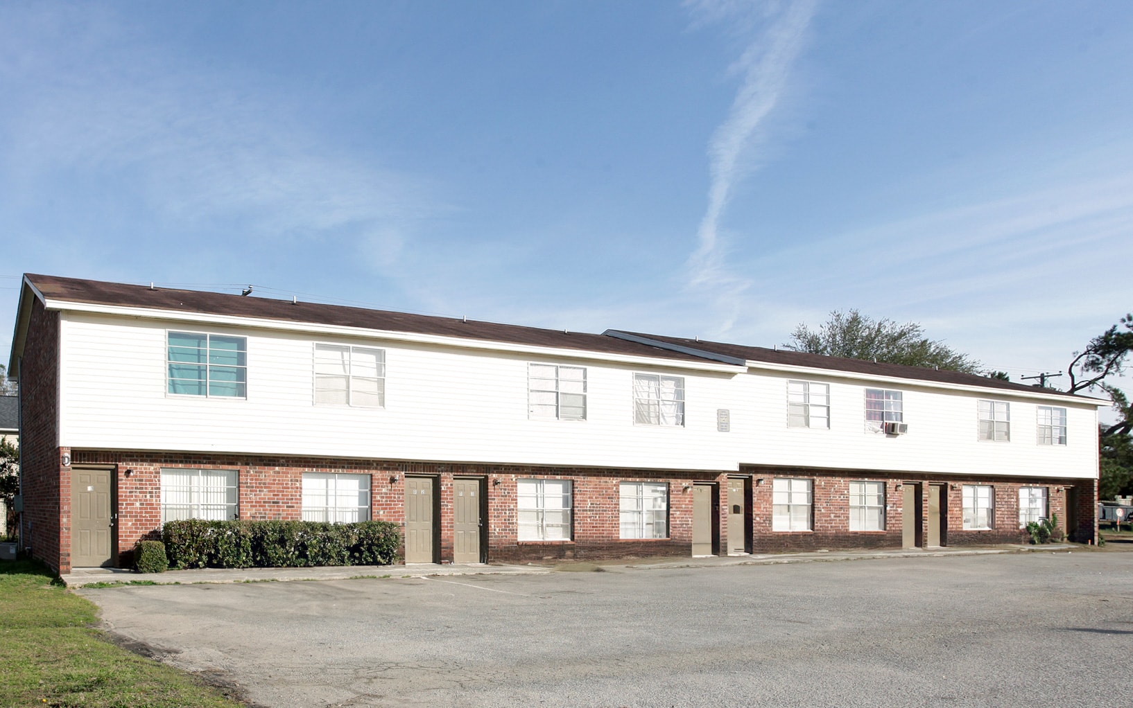A white building with red brick pillars and a grey roof.