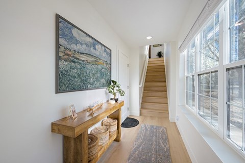 A hallway with a staircase and a painting on the wall.