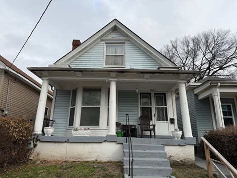 A blue house with a porch and a front yard.