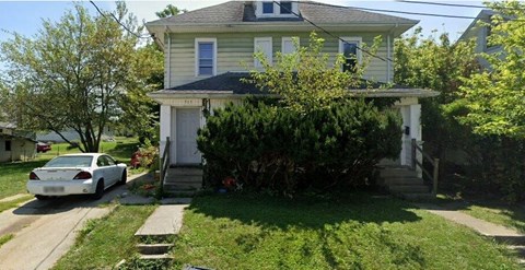 A white car is parked in front of a house.