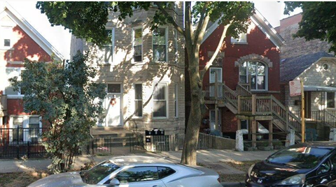 A tree in front of a red brick house.