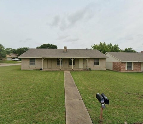A house with a white fence and a mailbox on the sidewalk.
