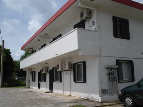 A white building with a red roof and a black van parked in front.