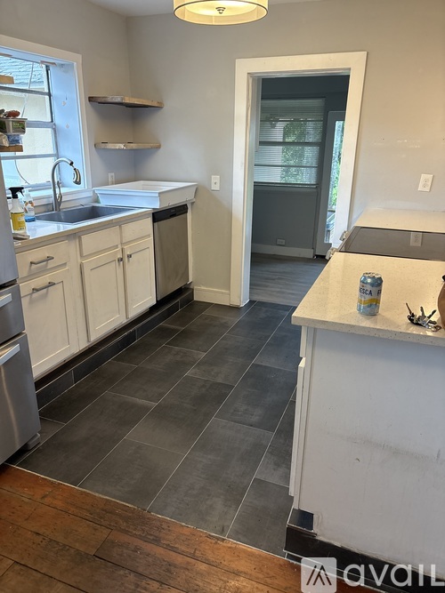 A kitchen with white cabinets and a grey floor.