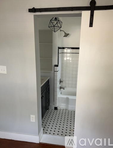 A bathroom with a white shower and a black and white tiled floor.
