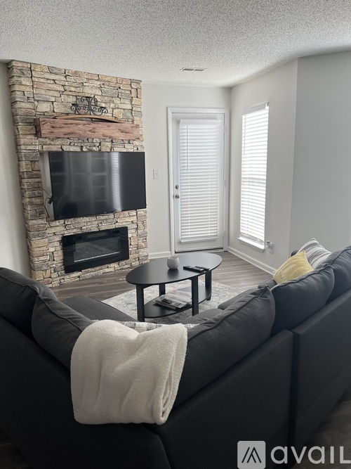 A living room with a stone fireplace and a grey couch.