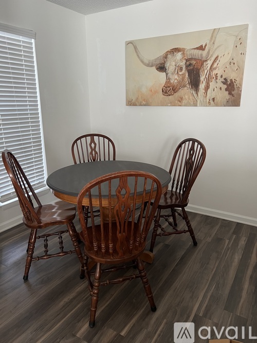 A dining room with a table and chairs and a painting of a bull on the wall.