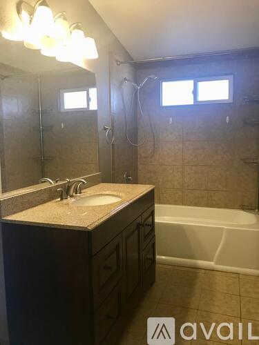 A bathroom with a sink, mirror, and bathtub.