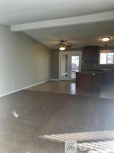 A spacious room with a ceiling fan and a door leading to another room.