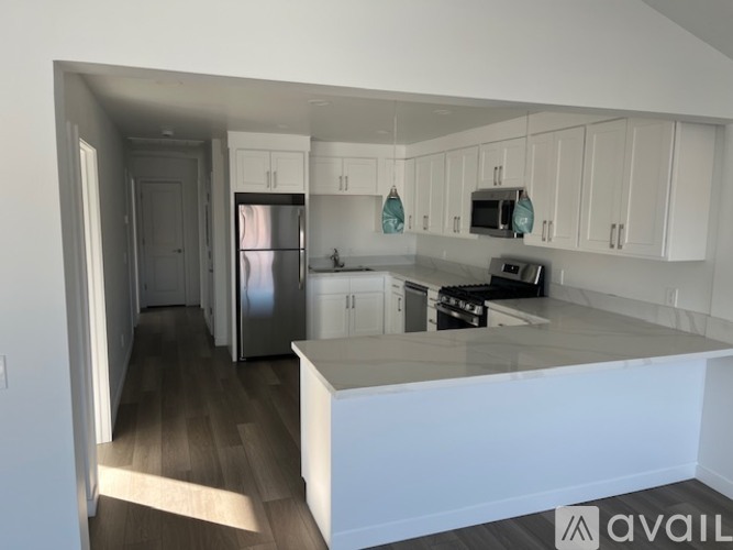 A kitchen with white cabinets and a stainless steel refrigerator.