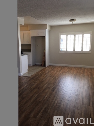 A room with wooden floors and a window with blinds.