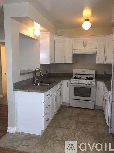 A kitchen with white cabinets and a black countertop.