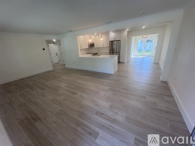 A spacious room with wooden flooring and white walls.
