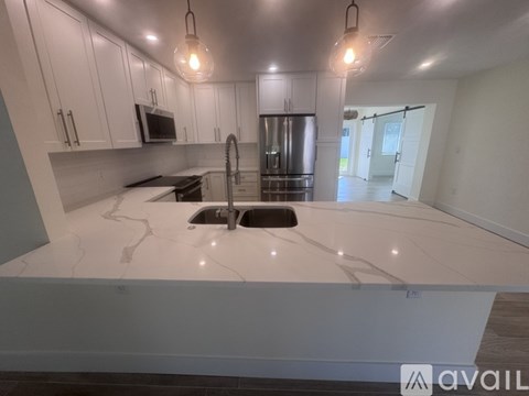 A kitchen with white cabinets and a marble countertop.