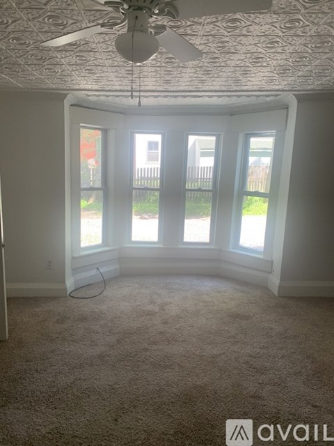 A room with a ceiling fan and carpeted floor.