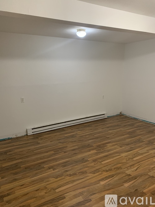 A room with wooden flooring and a white wall.