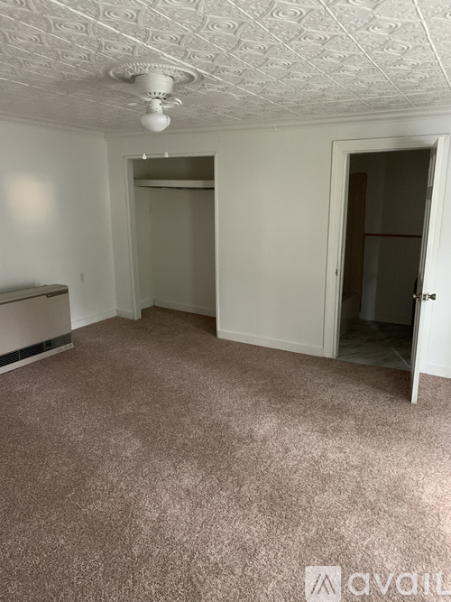 A room with a carpeted floor and a ceiling fan.