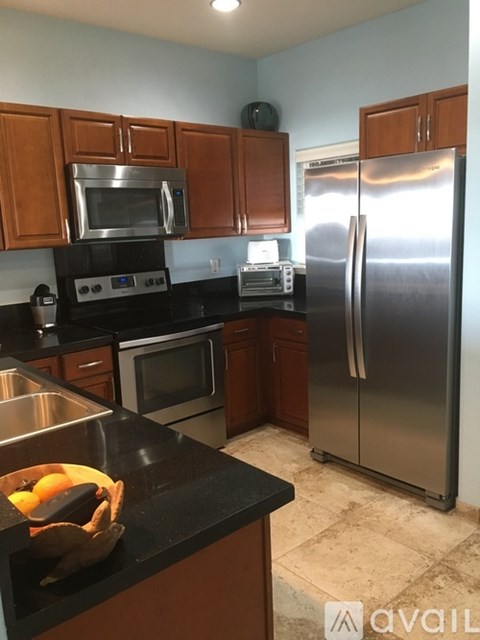 A kitchen with a black counter top and a stainless steel refrigerator.