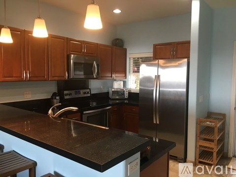 A kitchen with a black counter top and stainless steel appliances.