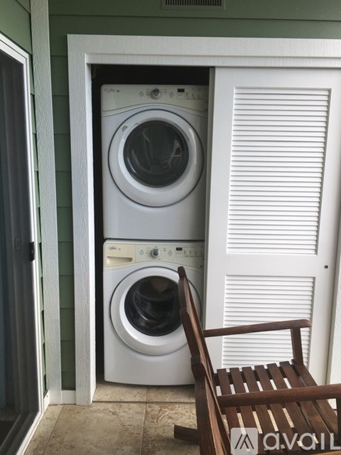 A white dryer and washer are stacked in a small space.