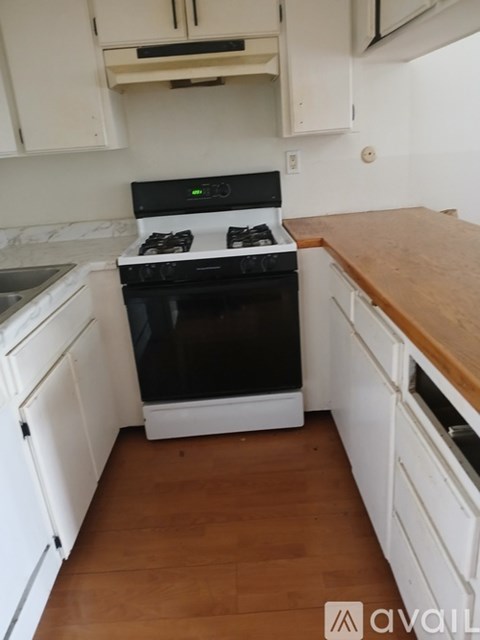 A black stove top oven in a kitchen with white cabinets.