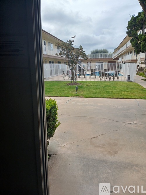 A view from a window of a courtyard with a playground and a building in the background.