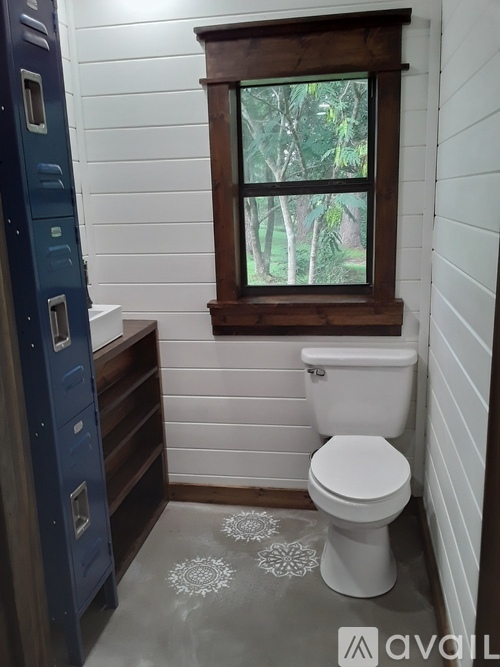 A bathroom with a toilet, a window, and a cabinet.
