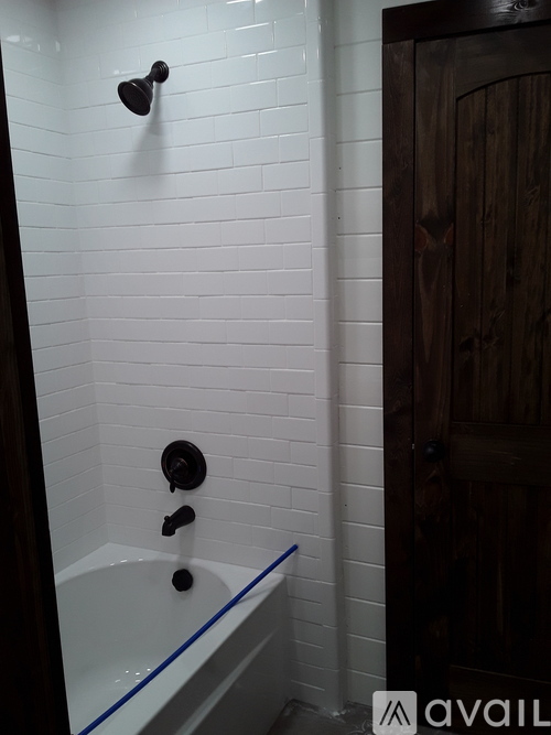 A white tiled bathroom with a wooden door.