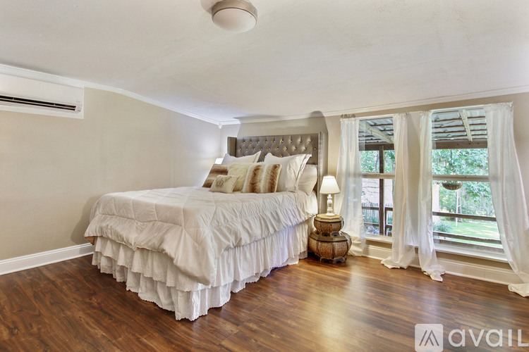 A bedroom with a large bed and a window with curtains.