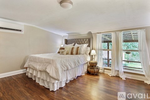 A bedroom with a large bed and a window with curtains.