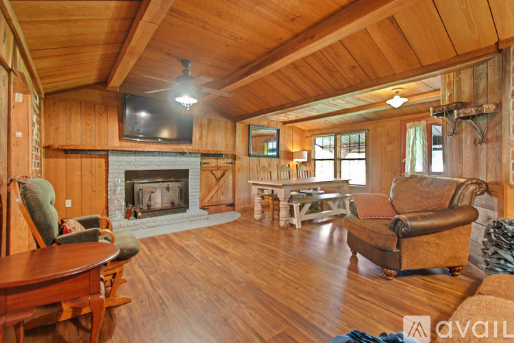 A cozy living room with a fireplace and wooden walls.