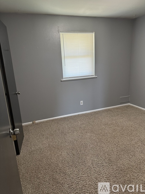 A room with a carpeted floor and a window with blinds.