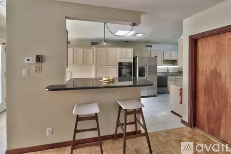 A kitchen with white cabinets and a black countertop.